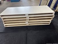 Stack of 5 white wood display shelves stacked and viewed from side showing shelving support structure underneath.