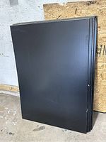 Eight black rectangular sheets stacked against a wall, smooth finish visible