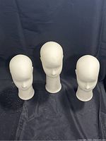 Front view of three white styrofoam jewelry head stands with evenly spaced arrangement.