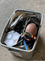 Top view of plastic storage box showing mini football, LED light plate, cables and electronic items inside.