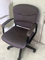 Photo showing the black fabric office chair angled view with armrests and caster wheels