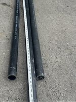 Close-up of pipe openings and measuring tape showing pipe length of approximately 95 inches.