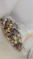 Large clear plastic bag filled with assorted antique to vintage buttons of various materials and colors.