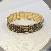 Front angle of gold-tone stretch bracelet adorned with rows of black rhinestones.