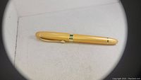 Beige capped fountain pen with gold-tone trim placed horizontally on a white textured cloth surface.