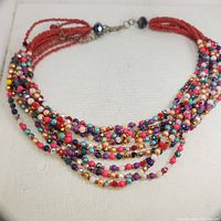 Close-up view showing many colorful small beads and red seed bead strands of the necklace