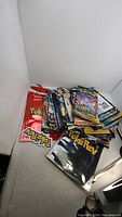 View of the bulk lot showing a pile of various Pokemon booster packs with a red Pokemon bag and black PokéRev folder.