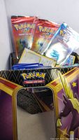 Pokemon TCG tin box open with visible booster packs and loose cards inside.