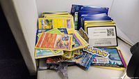 Various Pokémon cards and several sealed booster packs in a box.