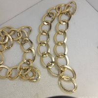 Photo showing two vintage bracelets placed on a white fabric surface, highlighting the large gold-tone links with textured finish.