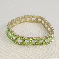Front and angled view of vintage expandable bracelet with green stones and silver-tone metal.