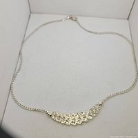 Silver necklace laid in a white display box showing the full chain and leaf design pendant.