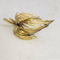 Side angled view of the antique gold leaf brooch showing texture and detailed design