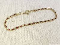 Front view of the Avon tennis bracelet showing alternating red and white stones with foldover clasp