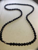 Full view of the black onyx faceted bead necklace showing the expanded length and barrel clasp connection.