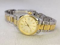 ESQ two-tone wristwatch angled to show the gold and silver bracelet and gold dial with date window.