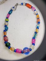 Photo showing the full colorful beaded necklace on a flat surface with varied glass beads in multiple colors and sizes.