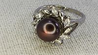 Top view close-up of vintage ring showing large black pearl centerpiece and surrounding clear marquise stones in silver-tone setting