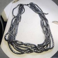Black enamel multi strand snake chain necklace twisted together and displayed on a mannequin bust.