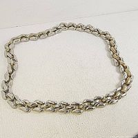 Full view of the large, heavy tri-link chain laid flat on a light surface showing the overall design and size.