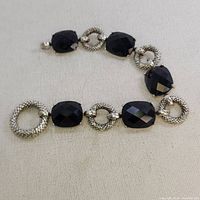 Full view of chunky vintage bracelet showing large faceted onyx stones alternating with textured sterling silver circular links and unique large circular clasp.