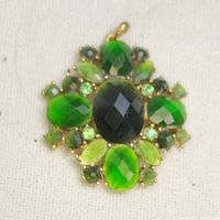 Overall view of vintage green faceted stone pendant on a fabric background