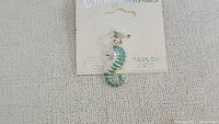 Photo of vintage sterling silver seahorse charm with green enamel on original card labeled 'Charm Charms'. The charm is attached to the card to show it is new and tarnish free.
