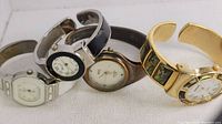 Four wrist watches laid side by side showing different band and bracelet styles
