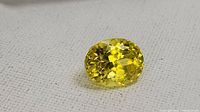 Top view of loose oval yellow sapphire on light background