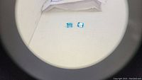 Photo showing two blue topaz gemstones placed side by side under magnification on white background
