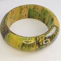 Front view of a large vintage bakelite cuff bracelet showing the marbled green, yellow, and black colors with a shiny polished finish.