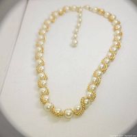 Close-up photo of vintage rope chain necklace with white round faux pearls arranged along twisted gold-tone rope chain, showing pearl drop extender.