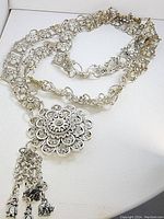 Full view of the vintage silver-tone necklace showing multi-strand chain with floral links and large floral pendant with dangling charms.