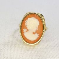 Front close-up of vintage cameo ring with profile carved in white on orange background set in gold band