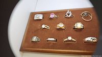 Top-down view showing thirteen assorted vintage rings arranged on a brown velvet-like fabric tray.