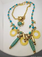 Full view of vintage turquoise necklace with gold-tone chain, beads, circular discs and decorative pendants showing details and clasp.