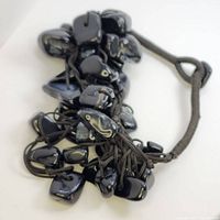 Top view of the black opal bead bracelet showing multiple beads strung on a dark braided cord with adjustable loop closure.