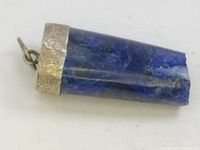 Close-up image of a lapis lazuli pendant with a textured 925 silver cap and bail, showcasing the blue stone's natural texture and silver's tarnished condition.