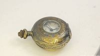 Angle view of the vintage mini pocket watch showing ornate metal casing with Roman numeral dial and winding crown.