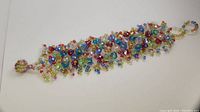Handmade mixed color briolette bead bracelet laid flat showing multi-colored faceted beads clustered densely creating a wide bracelet with beaded loop closure.