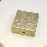 Front angle view of vintage Stanton snuffbox showing embossed design and letters on the lid.