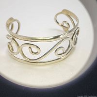 Close up of the silver cuff bracelet showing the intricate scrolling design and openwork metal.