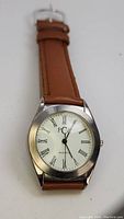 Front view of vintage PCA men's wristwatch showing white dial with Roman numerals and brown leather strap.