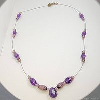 Full view of vintage purple fluorite bead necklace laid flat showing bead arrangement and lobster clasp.