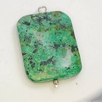 Front view of the green turquoise pendant showing natural matrix pattern and metal hanging loop and bottom prong.