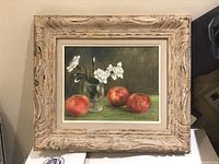 Framed painting of apples and white flowers on a green surface with dark brown background, rustic decorative wood frame