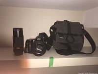 Photo showing Nikon telephoto lens, Nikon D80 camera with lens cap and strap, and National Geographic camera bag