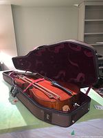 Cello and two bows secured inside open hard case on tabletop