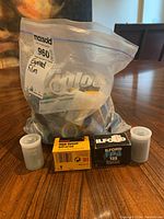 Ziploc bag filled with approximately two dozen expired 35mm camera film rolls including Kodak, Fuji, Ilford, some in boxes and some loose in canisters.