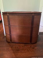 Front view of the large woven laundry hamper with visible woven wicker panels framed in dark wood.